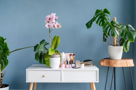 Stylish light room interior with elegant vanity table and plants, beauty and fashion