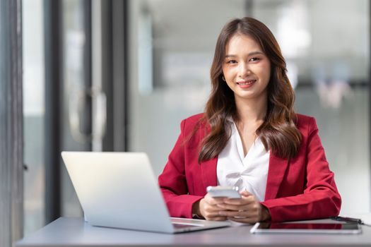 business woman holding smartphone getting message with confirmation making transaction on laptop computer at office.