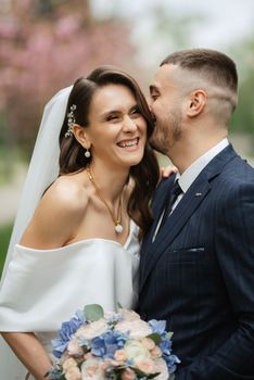 newlyweds walk in the park on the grass among cherry blossoms