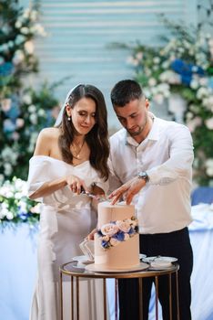 newlyweds happily cut, laugh and taste the wedding cake