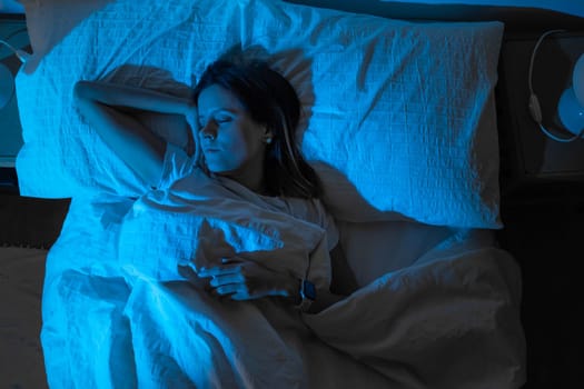 Top view of a beautiful girl sleeping cozily on a bed in her night room with Blue Colors from the moon. High quality photo