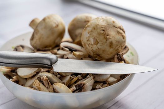 a bowl with pieces of fresh mushrooms. cut the mushrooms with a knife. Cooking mushroom dishes. Cooking dinner in the kitchen. Champignons