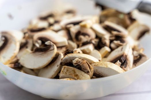 a bowl with pieces of fresh mushrooms. cut the mushrooms with a knife. Cooking mushroom dishes. Cooking dinner in the kitchen. Champignons