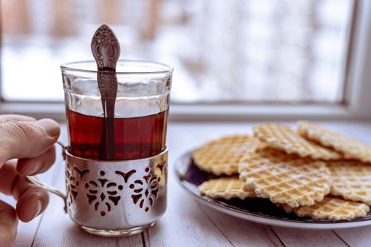 sweet delicious crispy waffles sprinkled with powdered sugar and a glass of tea in a vintage cup holder. Breakfast by the window. Top view