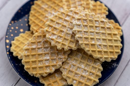sweet delicious crispy waffles sprinkled with powdered sugar on a plate by the window. Breakfast. Top view