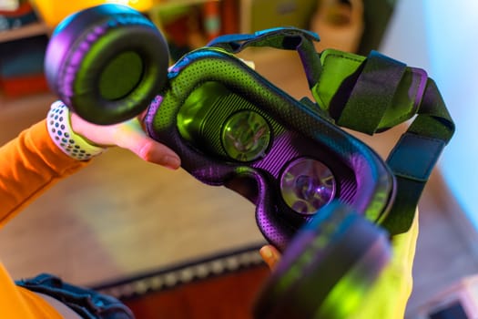 Wireless technologies. Young woman holding virtual reality glasses in the dark room with neon lighting.. High quality photo