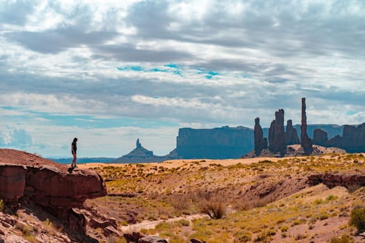 Young woman on the edge of a rock in Monument Valley during a sunny day. Travel freedom concept. High quality photo