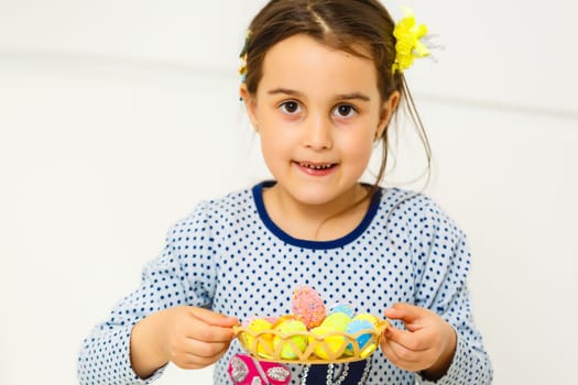 Cute smiling little girl with basket full of colorful easter eggs