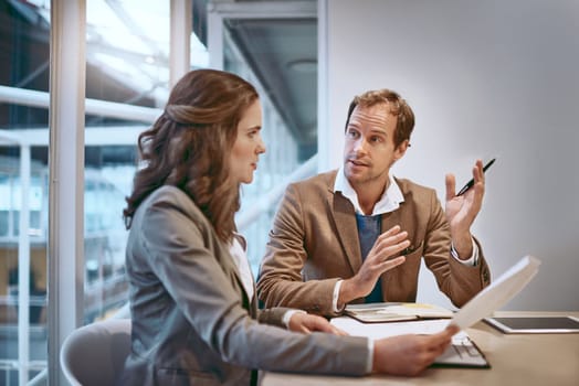 Communication is the key to synergy. two businesspeople working together in the boardroom