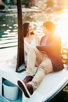 Man and woman are sitting at the bow of a boat, looking at each other. High quality photo