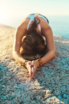 Yoga is my exercise of choice. a young woman doing yoga at the beach