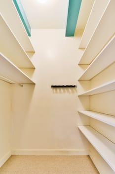 a walk - in closet with white shelvings and shelves on the wall, there is an open door