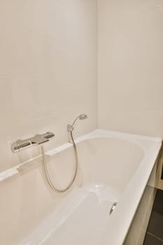 a white bathtub in the corner of a bathroom with black tiles on the walls and flooring around it