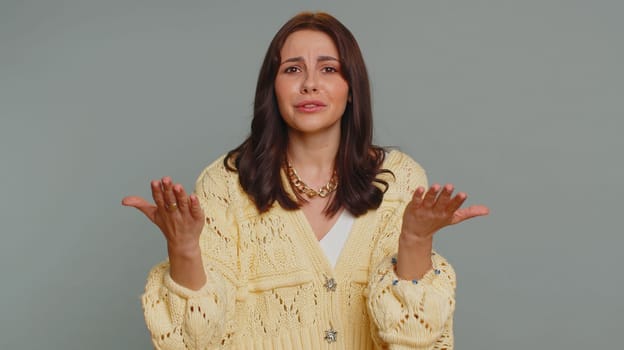 Quarrel. Displeased pretty young woman gesturing hands with irritation and displeasure, blaming scolding for failure, asking why this happened. Millennial girl isolated on gray studio background