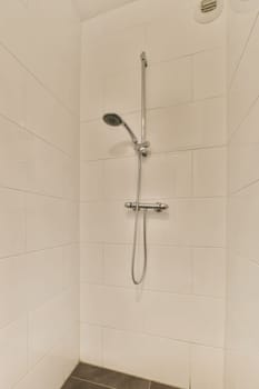 a shower with white tiles on the walls and black tile flooring in a tiled bathroom stall, which is also used as a