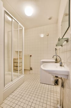 a bathroom with a sink, mirror and shower stall in the corner on the left is a white tiled floor