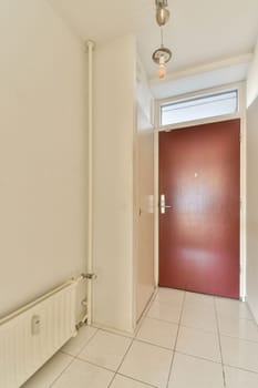 an empty room with a red door and white tiles on the floor in this photo is taken from the inside