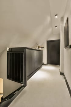 a room with white walls and black cabinetd cupboards on the left side of the room, there is a television mounted above