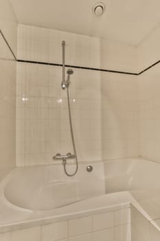 a bathtub in the corner of a bathroom with white tiles and black trim around the tub, which is attached to the shower