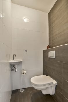 a modern bathroom with wood flooring and white tiles on the walls, along with a toilet in the corner