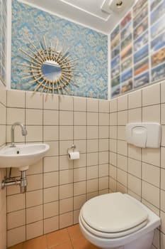 a bathroom with blue and white wallpapers on the walls, including a round mirror above the toilet bowl