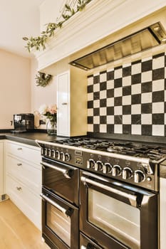 a kitchen with black and white tiles on the backs of the stoves, oven and dishwasher in it