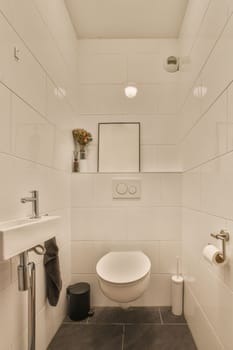 a small bathroom with white tiles on the walls and black tile flooring around the toilet, there is a mirror above the sink