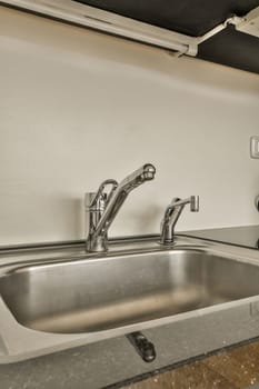 a kitchen sink and faucet in a room with white walls, wood flooring and gray counter tops