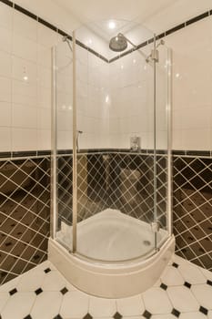 a bathroom with black and white tiles on the walls, shower stall and toilet in the floor is made out of marble