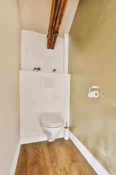 a toilet in the corner of a room with wood flooring and walls painted white, there is a light fixture on the wall