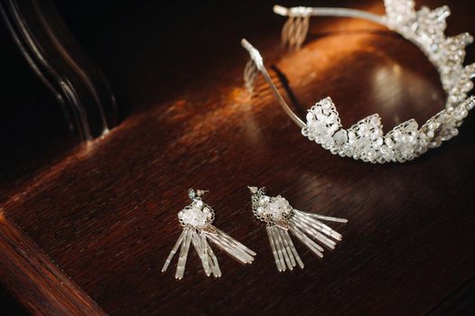 Wedding crown for the bride and earrings lie on the trellis.