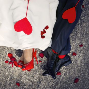 Close-up of lovers ' feet and two red hearts lying on them.