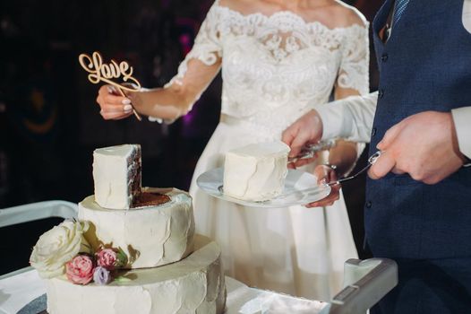 The bride and groom cut their wedding cake. beautiful cake with a cut and visible filling. wedding cake with the word love,the concept of the wedding.