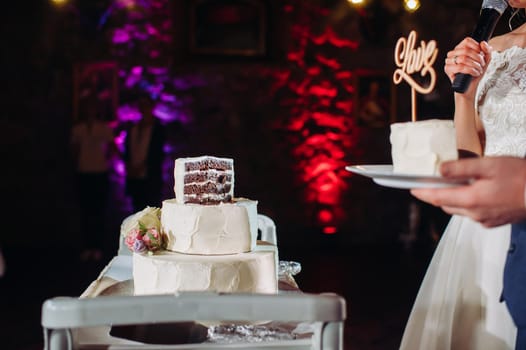 The bride and groom cut their wedding cake. beautiful cake with a cut and visible filling. wedding cake with the word love,the concept of the wedding.