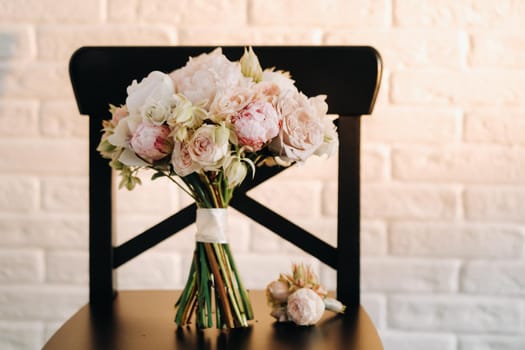 wedding bouquet with peonies and roses on a chair and boutonniere.The decor at the wedding.