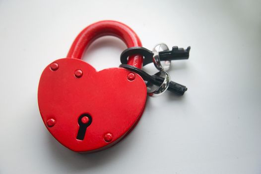Red lock with keys and two wedding rings on a white background.