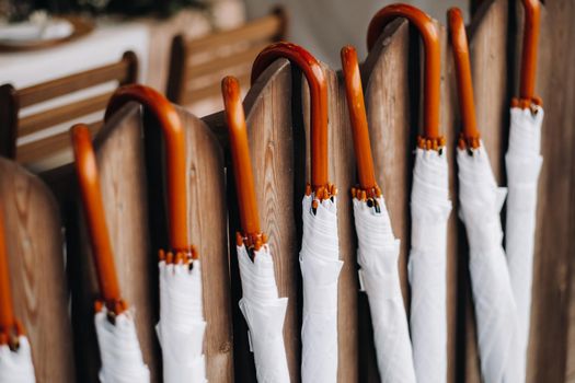 Wedding. Reception. White umbrellas with wooden handles Hang on the fence.