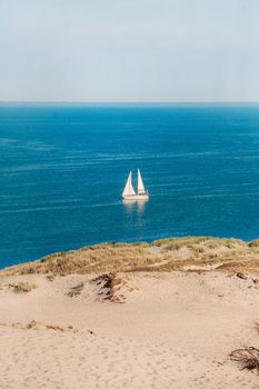 White Sailboat On the background of Dunes and Blue Sky in the sea.White sailboat in the Baltic sea.Lithuania.Nida.