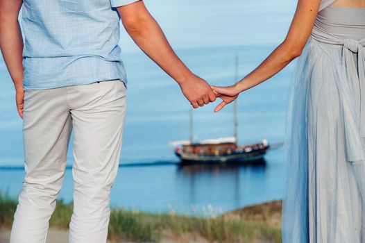 A couple in love stands on the beach in the dunes against the background of the Baltic sea and a ship, a Couple on the beach close-up in Lithuania, Nida.