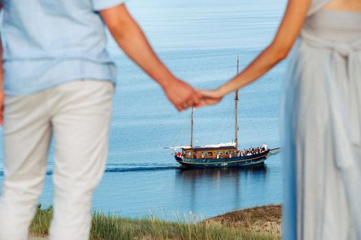 A couple in love stands on the beach in the dunes against the background of the Baltic sea and a ship, a Couple on the beach close-up in Lithuania, Nida.