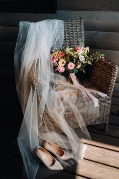wedding bouquet, veil and shoes of the bride are on a chair.