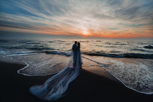 A couple in love at sunset on the background of the sea, an unrecognizable couple Portrait of a beautiful newlywed couple expecting a child. Photo