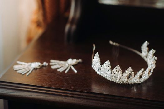 Wedding crown for the bride and earrings lie on the trellis.