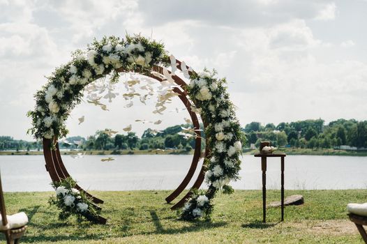 Wedding ceremony on the street on the green lawn.Decor with fresh flowers arches for the ceremony.