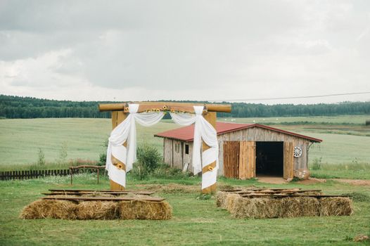 Wedding ceremony outside on a green lawn in a rustic style.Decor with arches of fresh flowers for the ceremony