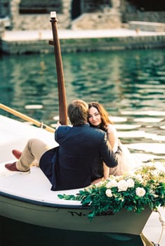 Man and woman hugging in a boat decorated with flowers. High quality photo