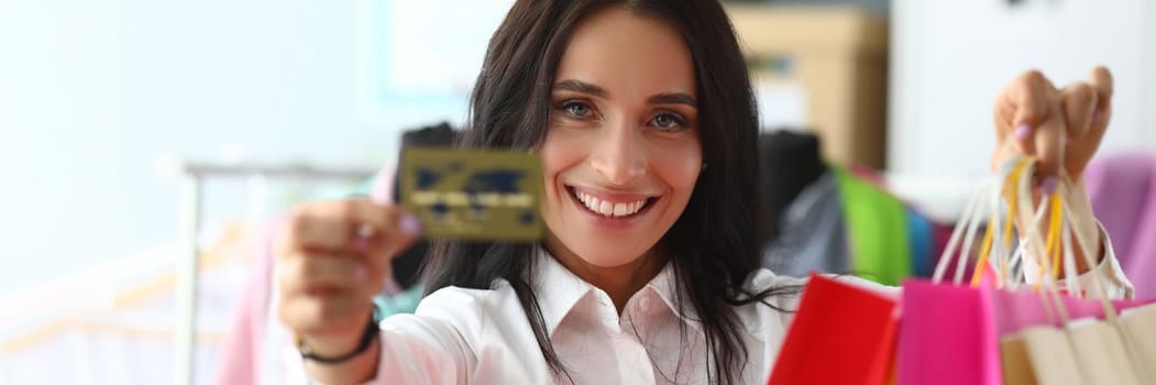 Portrait of woman holding shopping bags in store with bank credit card. Favorable shopping discounts and sales
