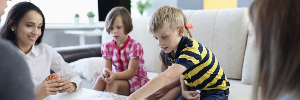 Parents and children play board game together at table. Games for whole family at home