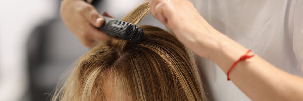 Pulling strands of hair with professional iron care. Keratin straightening and hair restoration