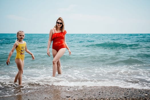 Happy loving family mother and daughter having fun together on the beach. Mum playing with her kid in holiday vacation next to the ocean - Family lifestyle and love concept.